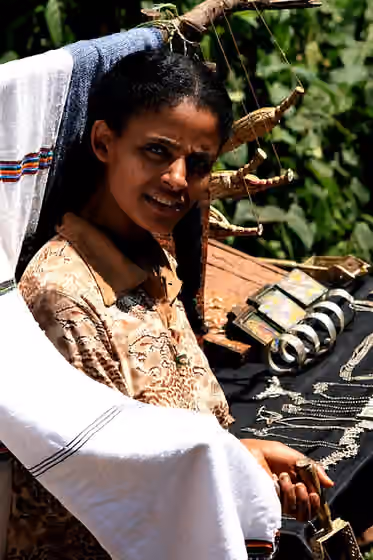orang Amhara — Woman selling traditional souvenirs, along a dusty path.