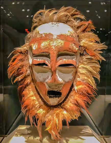 Nyindu people — This photograph captures a striking image of a Nyindu face mask, accompanied by an ornate feathered collar.