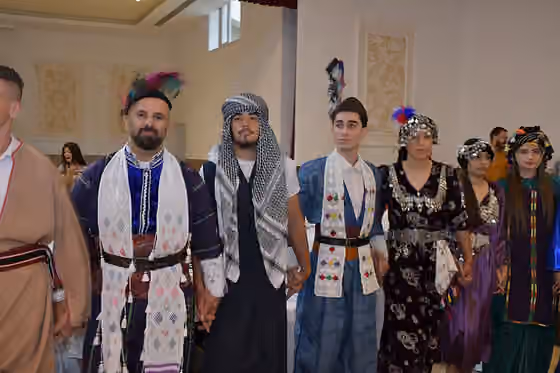 orang Asiria — A picture of Assyrians forming a Khigga dance line while wearing traditional Khomala