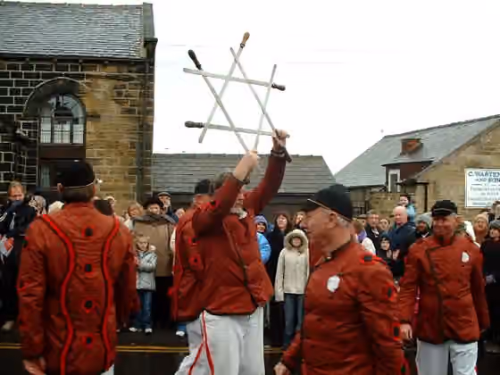 Long sword dance — Description: Boxing Day 2005 - The Grenoside Sword Dance Captain holds aloft the sword lock before placing it around his neck.